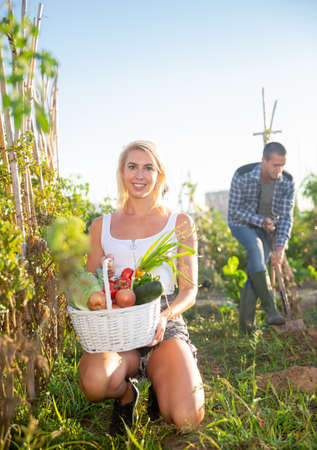 Positive woman posing with harvest of vegetables in gardenの写真素材