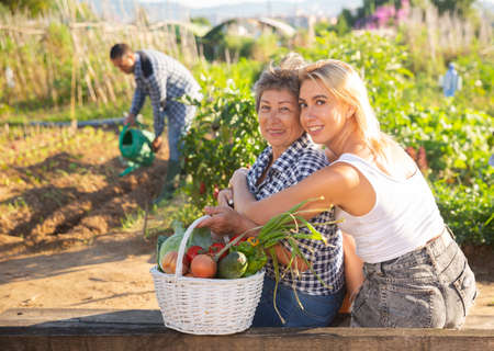 Smiling girl hugging elderly mother in home gardenの写真素材