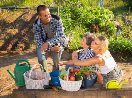 Friendly family discussing good crop of vegetables in gardenの写真素材