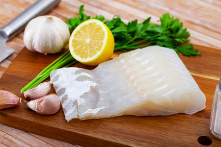 Fresh raw kingklip fillet with greens, lemon and spicesの写真素材