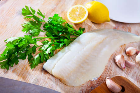 Fresh cod fillet with parsley on wooden boardの写真素材