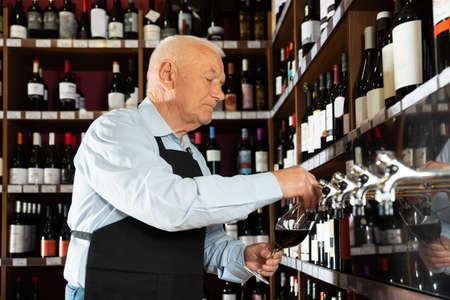 man professional sommelier pouring wine from wine columnの写真素材