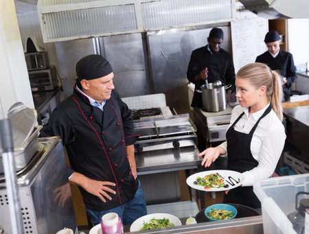 Bewildered chef talking with waitress