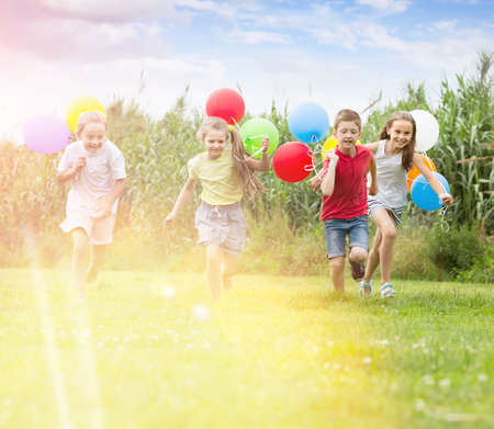 Four happy kids running on green lawnの写真素材