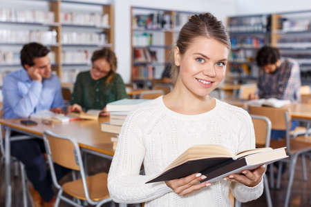 female student browsing textbooks in university libraryの写真素材