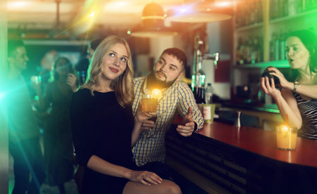 Young man flirting with women on party and drinking cocktails