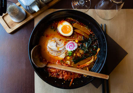 Traditional japanese noodle soup with shiitake mushroom, egg and greens served in ceramic bowl with wooden chopsticksの写真素材