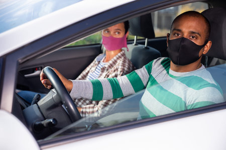 Latin American man in protective mask driving car