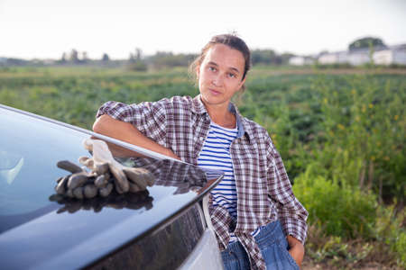 Female farmer posing near car on farmの写真素材