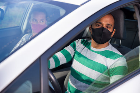 Latin American man in protective mask driving car