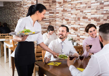 Smiling young waitress serving meal for restaurantの写真素材