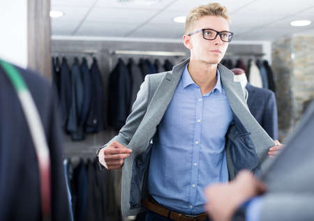 Male buyer in the glasses trying jacketの写真素材