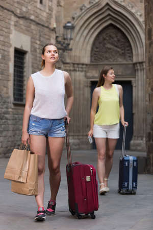 female tourists exploring old european city with baggageの写真素材