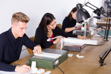 Young man working on scroll saw in architecture modeling workshop