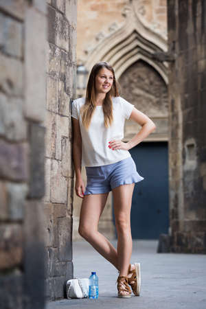 Young woman standing near old stone wallの写真素材
