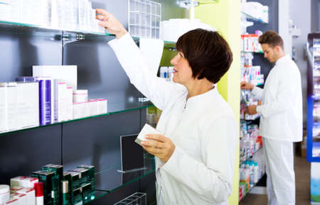 Pharmacist and pharmacy technician posing in drugstoreの写真素材