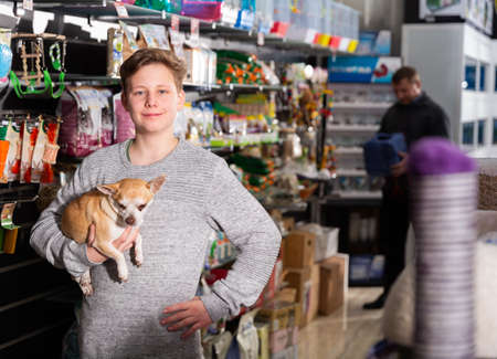 Portrait of happy teen boy with his little dog visiting pet supplies shopの写真素材