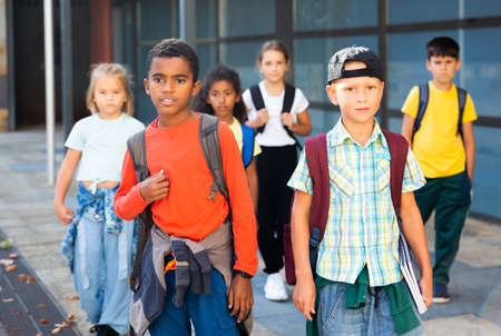 Preteen schoolchildren with rucksacks going to collegeの写真素材