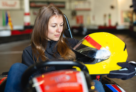 Female racer holding helmet on kart track