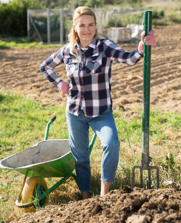 Woman farmer loading garden wheelbarrow with manureの写真素材