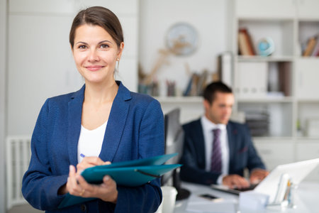Smiling female business assistant noting tasks on clipboard