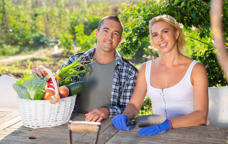 Couple posing with harvested vegetables in garden