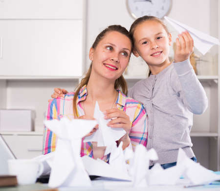 Woman and girl making airplanes of papeの写真素材