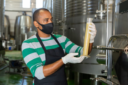 Winemaker in protective masks analyze the white wine in beaker