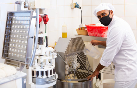 Baker controlling dough making in kneading machine in bakery