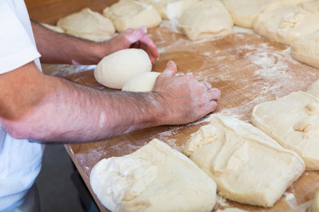 Closeup shot of bakers hand preparing dough in bakery