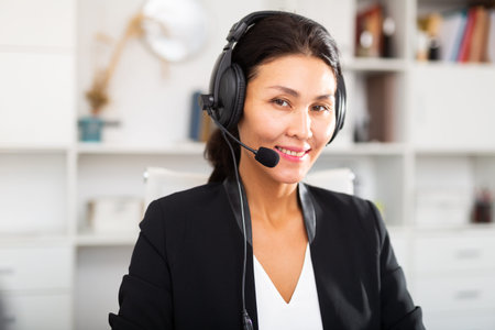 Portrait of woman call centre operator with headphones in office