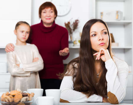 Mother upset after quarrel with daughter standing behind with grandmaの写真素材