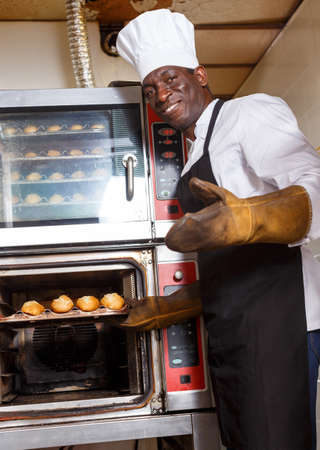 Baker controlling process of baking bread in ovenの写真素材