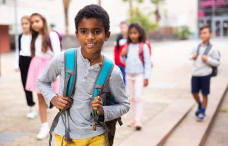 African american boy standing near school, children on backgroundの写真素材