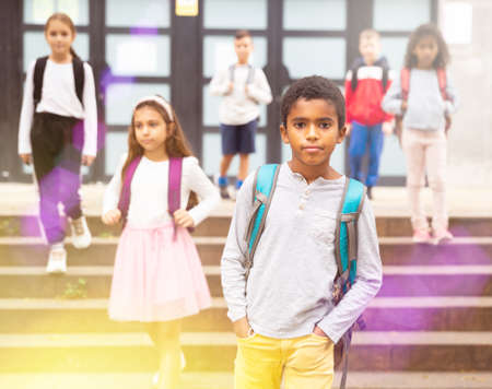 African american boy standing near school, children on backgroundの写真素材