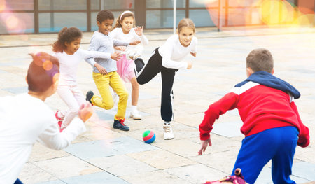 Group of happy schoolchildren playing football together