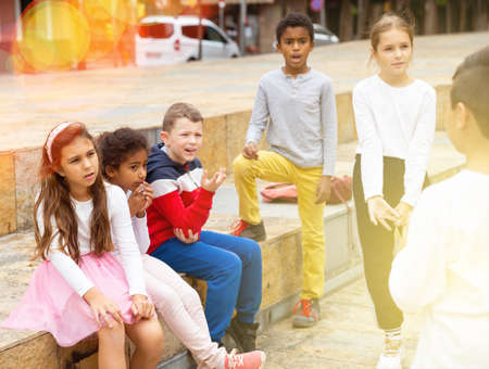Group of smiling children sitting on stairs and chatting togetherの写真素材