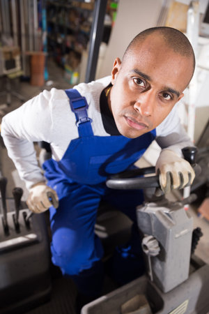 Closeup face of confident hispanic warehouse worker driving forklift