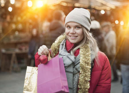 Happy girl chooses Christmas toys on the street marketの写真素材