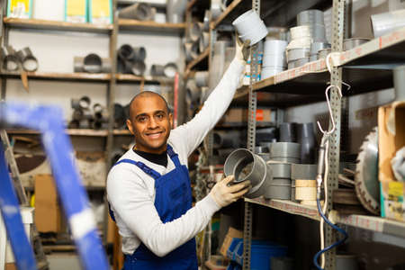 Smiling hispanic foreman looking for PVC pipes in building hypermarketの写真素材