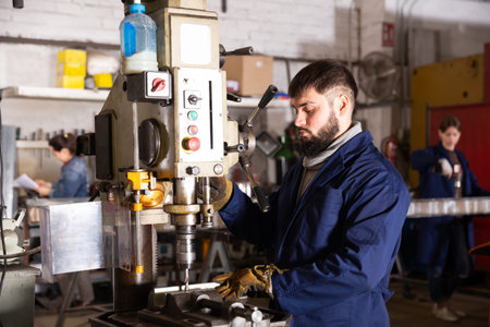 Portrait of man working with drilling machine on metal plate
