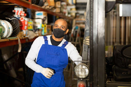 Foreman drives forklift in protective mask at the warehouse of hardware storeの写真素材
