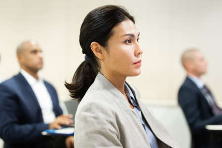 Concentrated Asian businesswoman listening to business seminarの写真素材