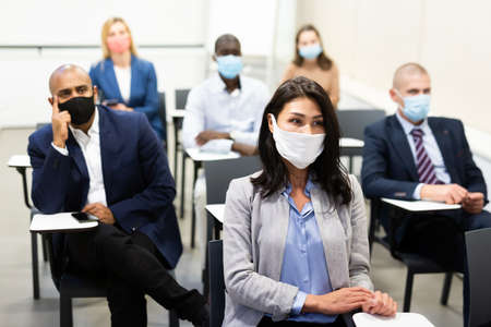 Asian businesswoman in protective mask participating in corporate seminarの写真素材