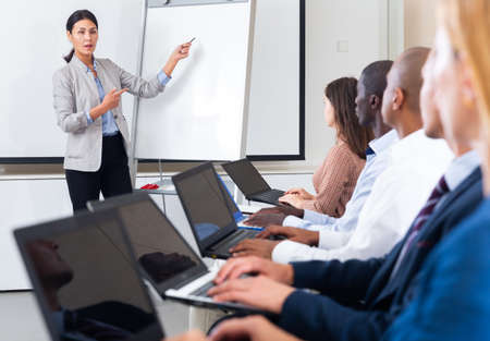 Asian businesswoman giving report to partners sitting with laptopsの写真素材