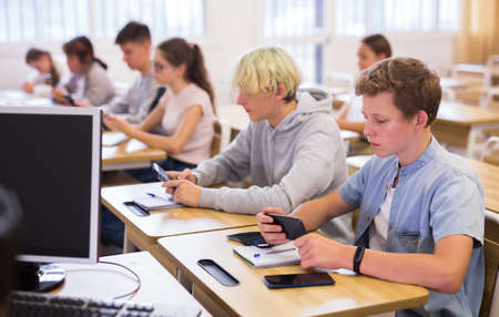 Teenage students using smartphones during lessonの写真素材