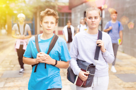 Students with backpacks and notebooks walk down the street