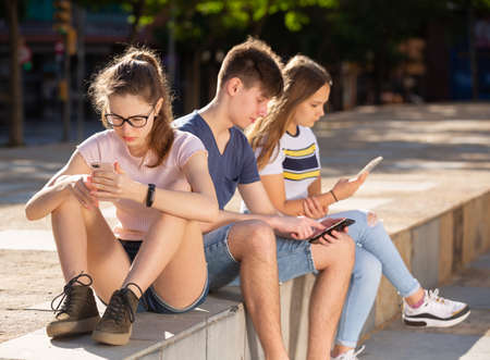 Teenagers chatting on their smartphone on walkingの写真素材