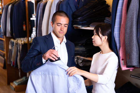 Female shopping assistant offering various shirts in mens cloths storeの写真素材