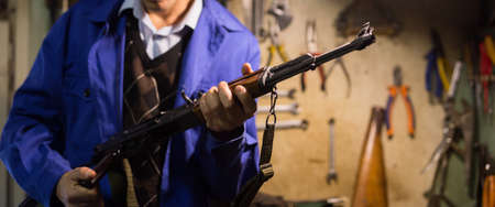 assault rifle in hands of gunsmith in weapons workshopの写真素材
